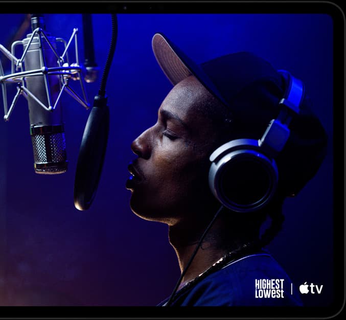 iPad Pro, landscape orientation, front exterior, space black color, rounded corners, black display bezel, display showing Apple TV playing a scene from  the Apple TV original film Highest 2 Lowest with ASAP Rocky as Yung Felon rapping into a microphone